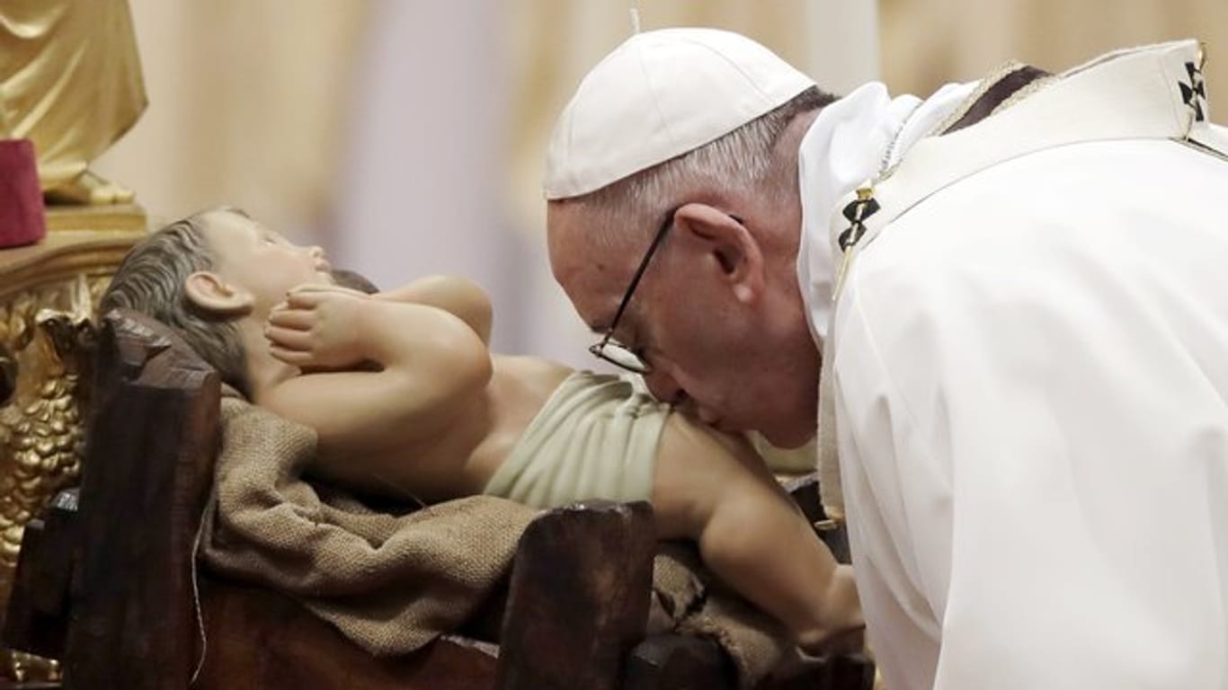 Papst Franziskus küsst bei der Weihnachtsmesse im Petersdom im Vatikan das Christuskind.