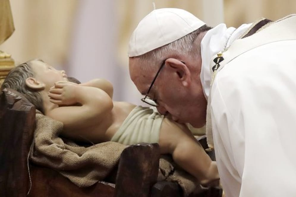 Papst Franziskus küsst bei der Weihnachtsmesse im Petersdom im Vatikan das Christuskind.