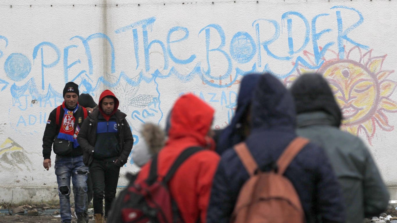Mehrere Flüchtlinge stehen im Dezember in Sid (Serbien), nahe der Grenze zu Kroatien, vor einer Mauer mit der Aufschrift "Öffnet die Grenze". (Symbolbild)