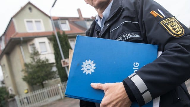 Ein Polizist geht in Karlsruhe an einem Wohnhaus vorbei, in dem der Verdächtige gewohnt haben soll.
