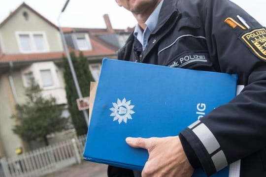 Ein Polizist geht in Karlsruhe an einem Wohnhaus vorbei, in dem der Verdächtige gewohnt haben soll.