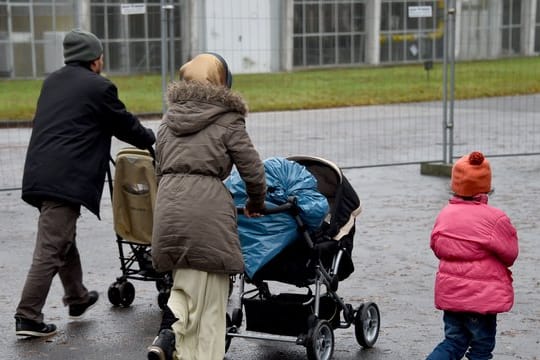 Eine Flüchtlingsfamilie geht in Boostedt über das Gelände einer Erstaufnahmeeinrichtung.