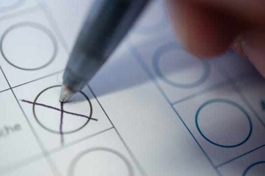 Eine Frau macht bei einer Wahl ein Kreuz auf einem Stimmzettel.
