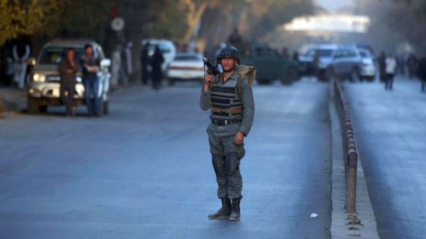 Ein bewaffneter Polizist sperrt nach einem Anschlag in Kabul eine Straße ab.