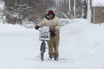 Ein Bewohner von Erie (US-Bundesstaat Pennsylvania) schiebt sein Fahrrad durch den Schnee.