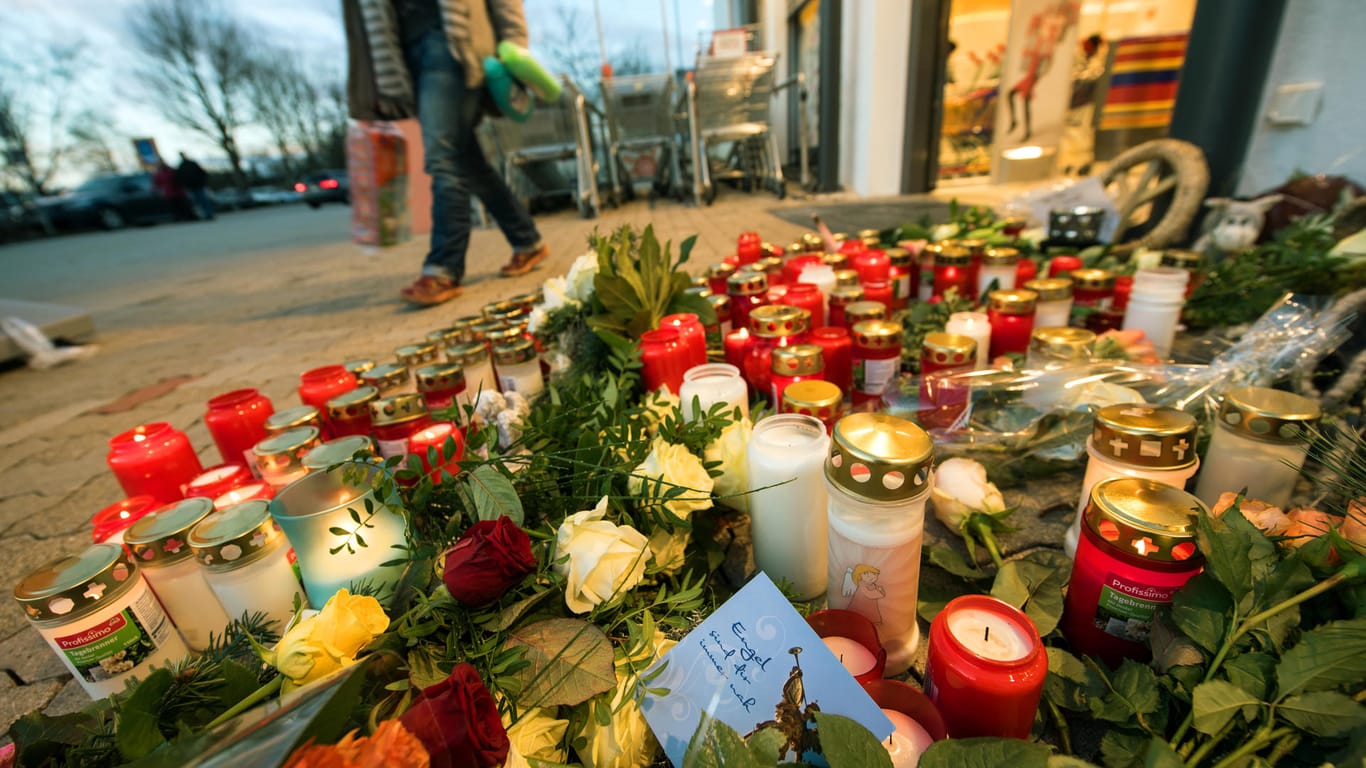 Ein Zettel mit der Aufschrift "Engel sind für immer nah" liegt vor dem Drogeriemarkt in Kandel zwischen abgelegten Blumen und Kerzen.
