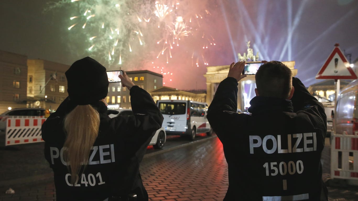 Silvester 2016: Polizisten fotografieren das Feuerwerk über dem Brandenburger Tor in Berlin.