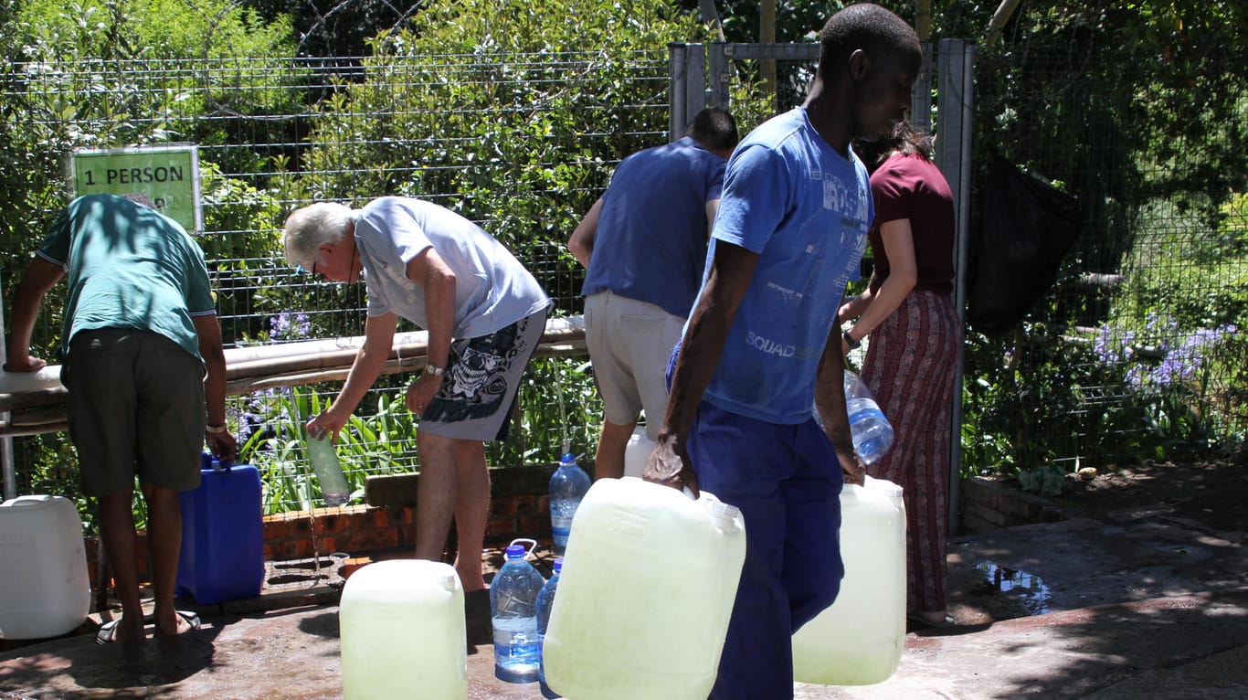Bürger füllen Wasserkanister an einer natürlichen Quelle auf.