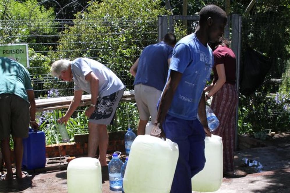 Wasser schleppen: Bewohner von Kapstadt füllen Wasserkanister an einer natürlichen Quelle in auf.