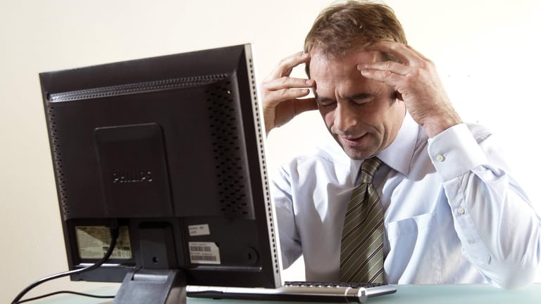 Ein Geschäftsmann angestrengt am PC: Viele Menschen sind im Job gestresst.