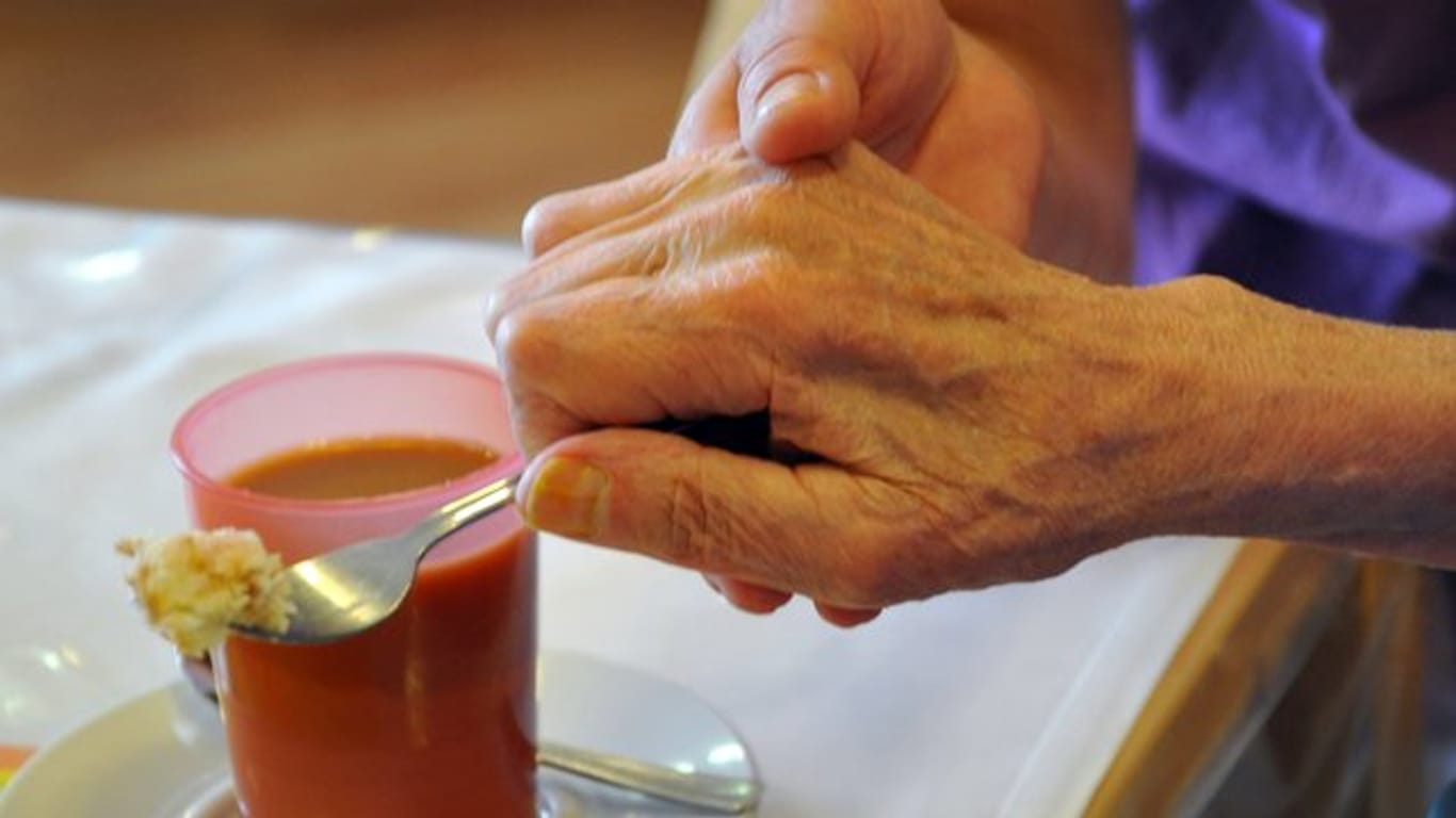 Eine Altenpflegerin unterstützt in einem Pflegeheim eine Frau beim Essen.