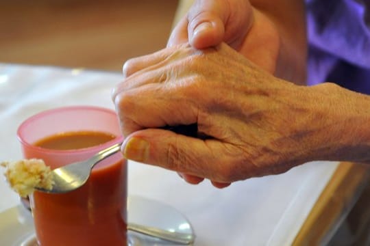 Eine Altenpflegerin unterstützt in einem Pflegeheim eine Frau beim Essen.