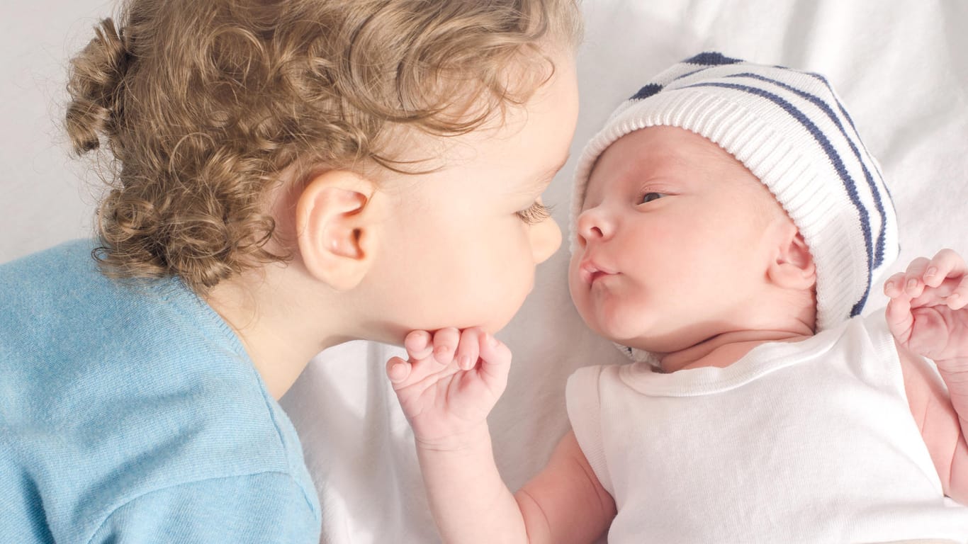 Großer Bruder küsst neues Geschwisterkind: Veränderung in der ganzen Familie durch Neugeborenes