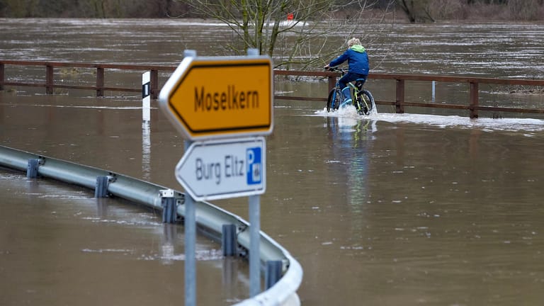 Ein Radfahrer fährt über die vom Moselhochwasser überflutete Bundesstrasse B416 bei Moselkern (Rheinland-Pfalz): Mit einem weiteren Anstieg der Pegelstände wird in den nächsten Tagen gerechnet.