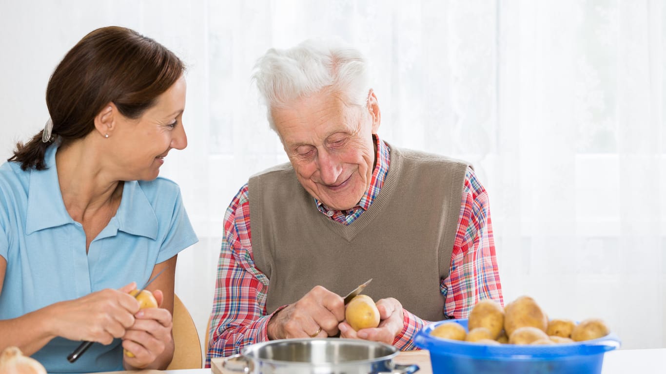 Pflegerin hilft Rentner in der Küche: Allein leben ist auch mit Demenz noch möglich.
