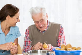 Pflegerin hilft Rentner in der Küche: Allein leben ist auch mit Demenz noch möglich.