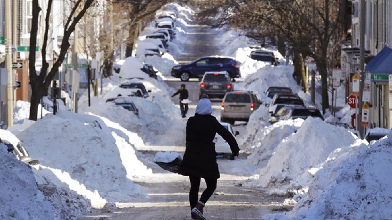 Eine Frau schaufelt im Süden von Boston Schnee von der Straße.