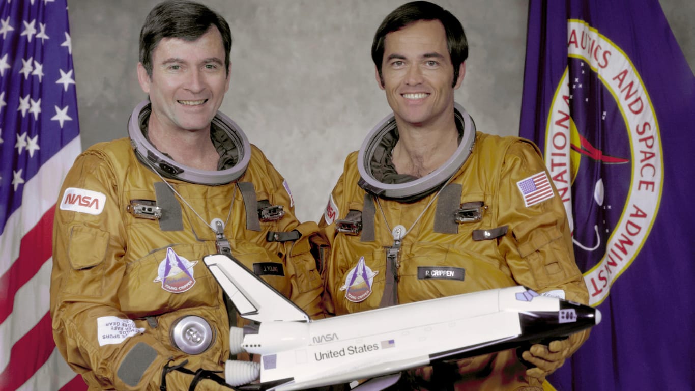 John Young (l.) und Robert Crippen halten ein Modell eines Space Shuttles.