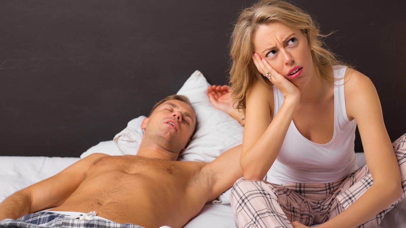Die Frau ist genervt, während ihr Mann schläft.