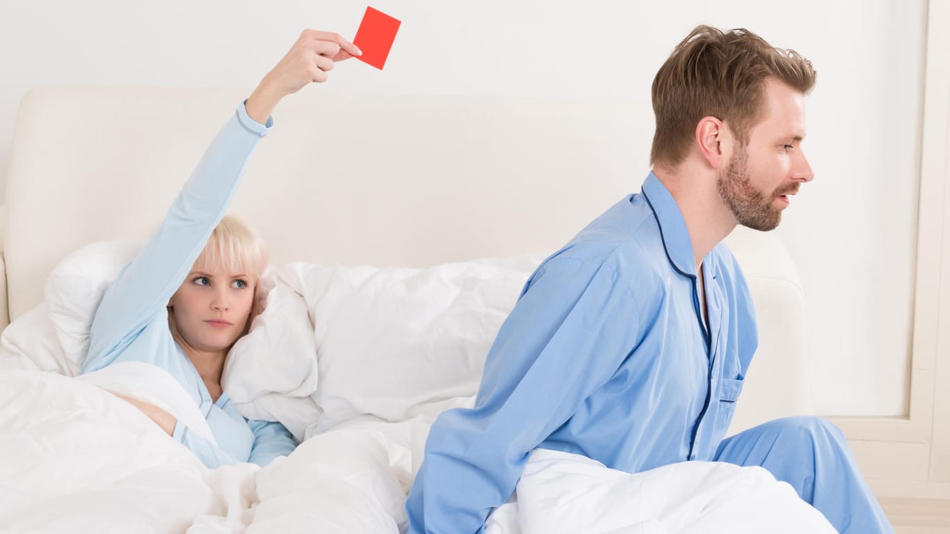 Frau zeigt Mann rote Karte im Bett.