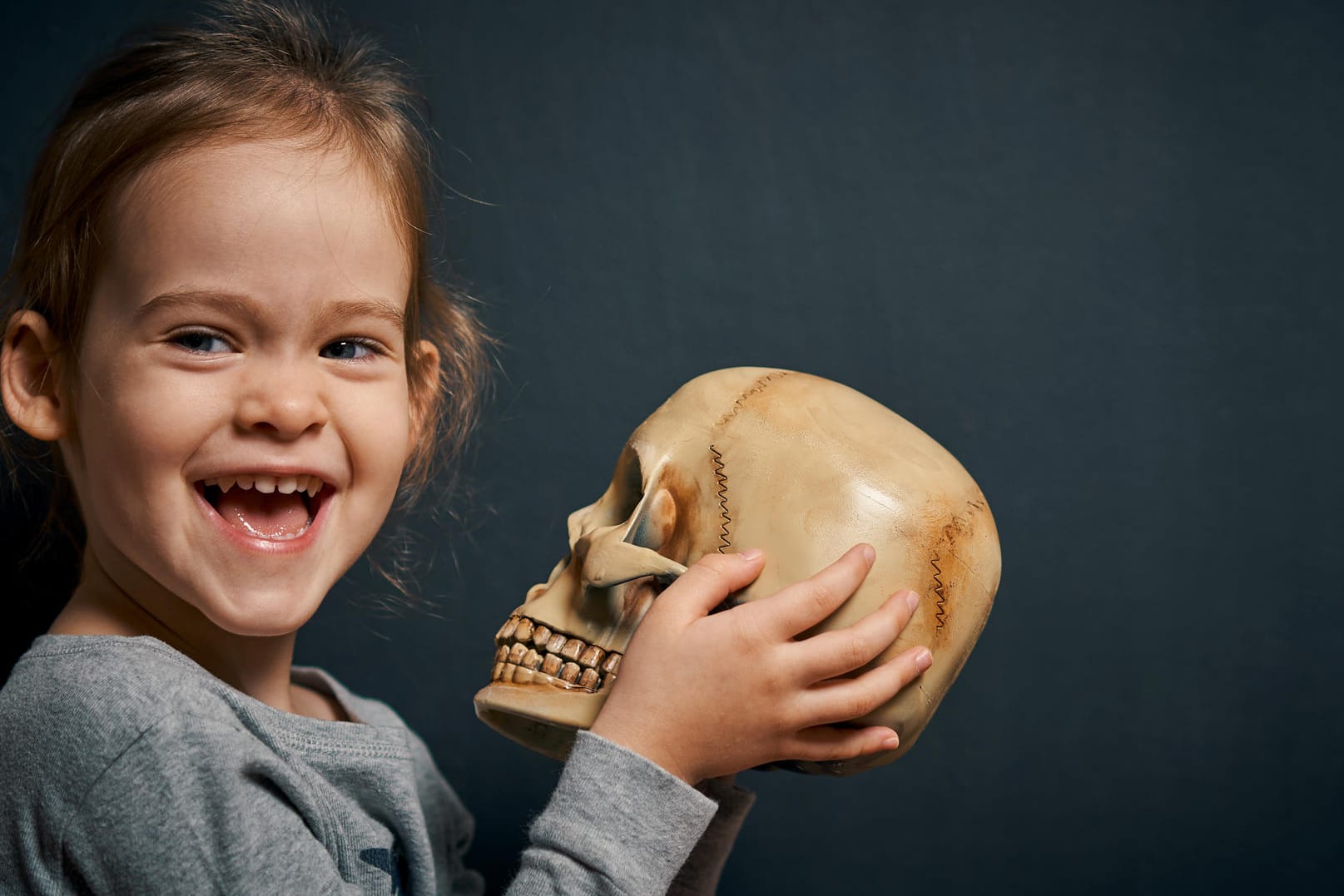 Niedliches Mädchen hält lachend einen Totenkopf fest