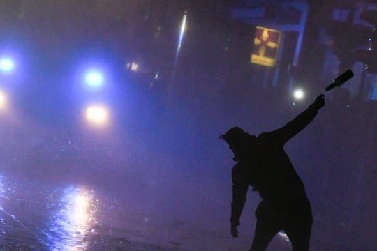 Ein Demonstrant attackiert bei den G20-Krawallen in Hamburg einen Wasserwerfer mit einem Flaschenwurf.