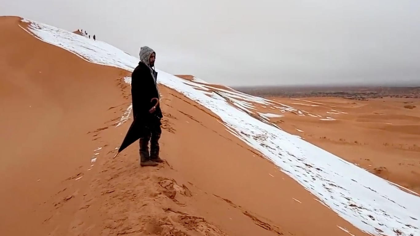 Ein Mann am Rande einer schneebedeckten Düne bei Ain Sefra in der Sahara.
