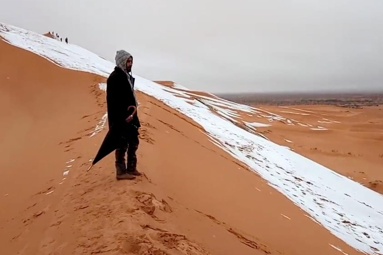 Ein Mann am Rande einer schneebedeckten Düne bei Ain Sefra in der Sahara.