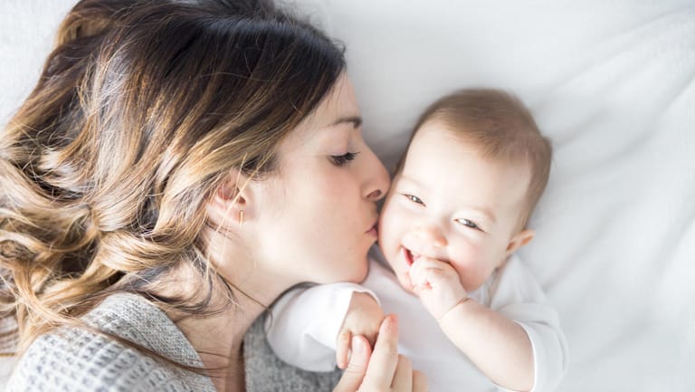 Eine Mutter küsst ihr Baby: Der Nachwuchs braucht körperliche Nähe.