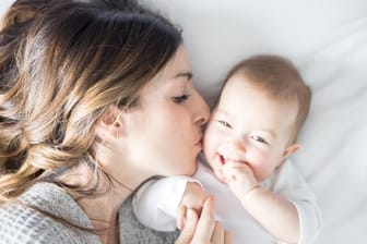 Eine Mutter küsst ihr Baby: Der Nachwuchs braucht körperliche Nähe.