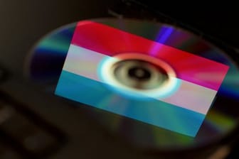 Die Fahne des Großherzogtums Luxemburg spiegelt sich in einer CD im Laufwerk eines Computers.