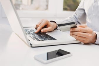 Mann betreibt Online-Banking über den Laptop: Ein Antivirenprogramm und eine Firewall sind notwendig für Ihren Computer, um sich vor Fremdeingriffen zu schützen.