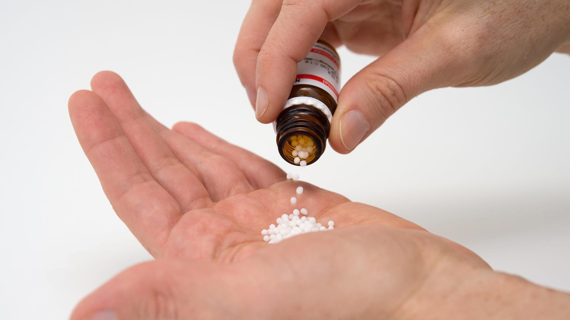 Hand mit Globulis: Fünf Menschen berichten über ihre Erfahrungen mit Homöopathischen-Arzneimitteln.