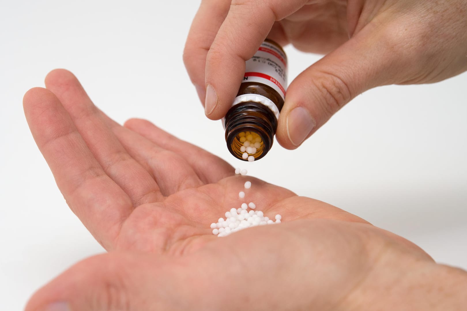 Hand mit Globulis: Fünf Menschen berichten über ihre Erfahrungen mit Homöopathischen-Arzneimitteln.