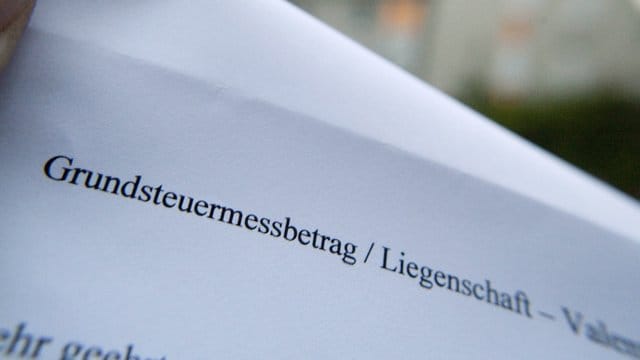 Ein Reihenhausbesitzer hält einen Grundbesitzabgabenbescheid der Stadt in der Hand. Ein Reihenhausbesitzer hält einen Grundbesitzabgabenbescheid der Stadt in der Hand.