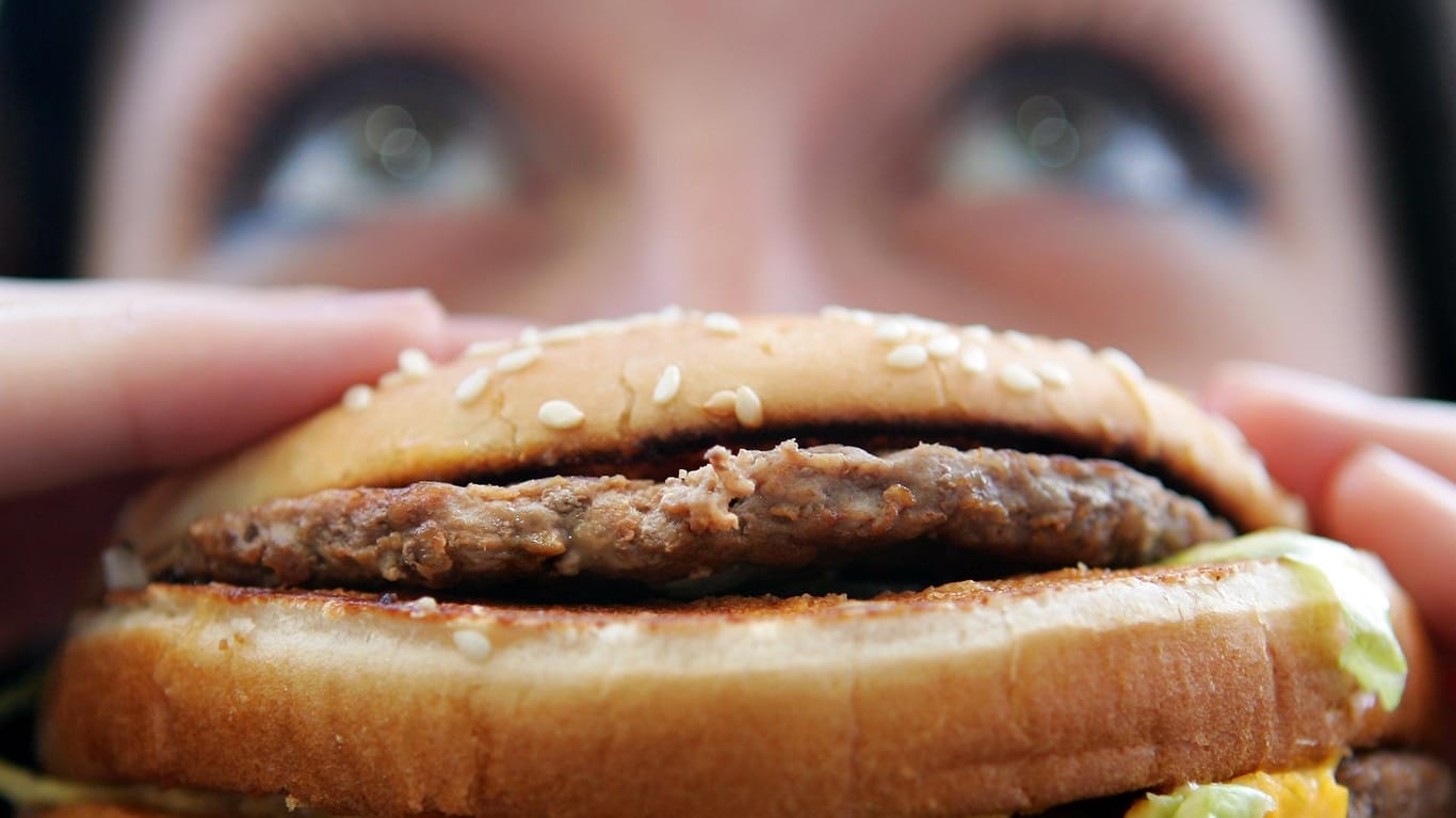 Eine Frau beißt in einen Burger: Die Universität Bonn hat die Auswirkungen von Fastfood auf das Immunsystem untersucht.