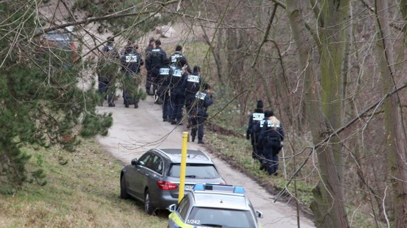 Polizisten suchen in einem Waldstück am Pfingstbergweiher nach Spuren.