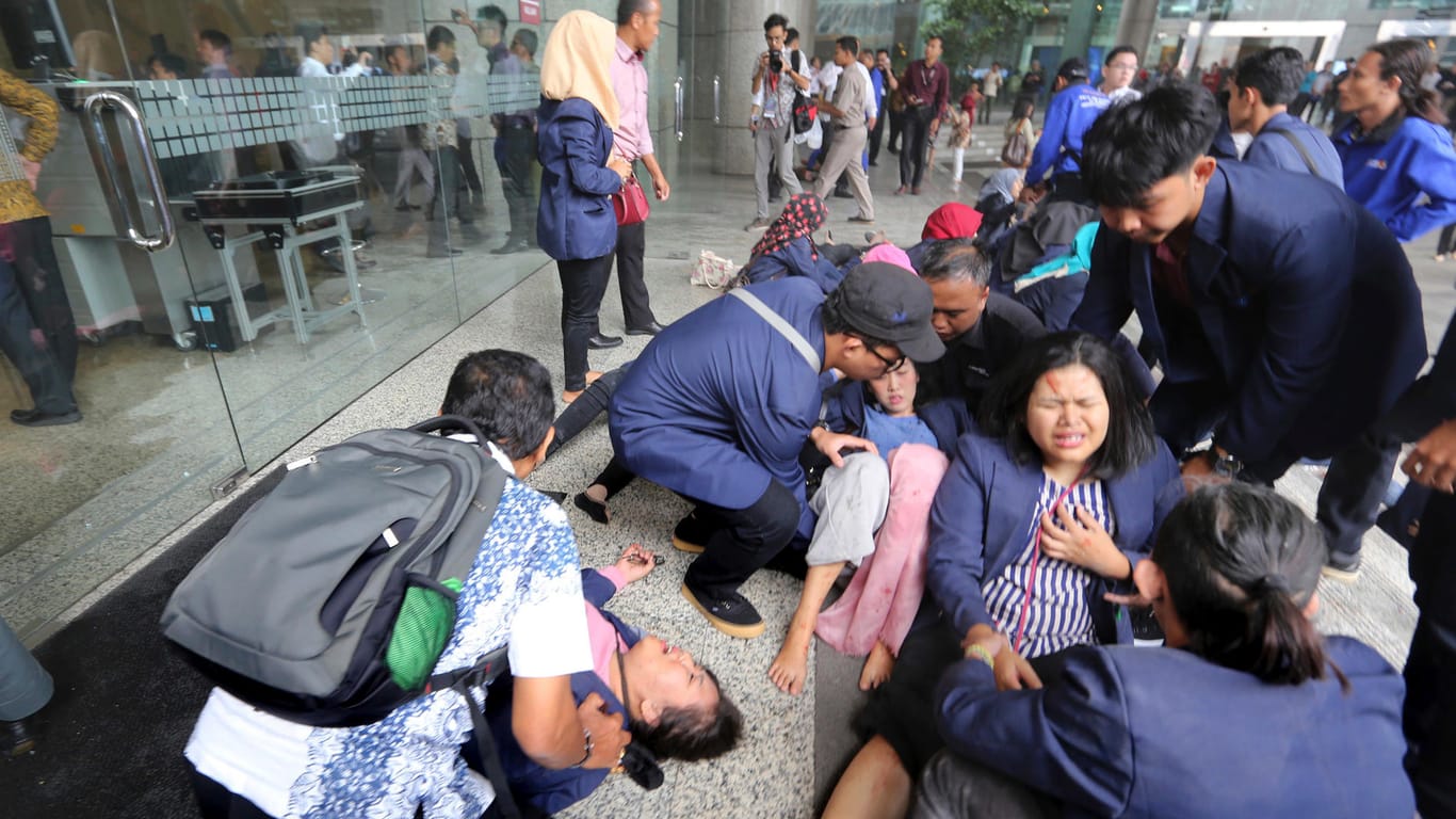 Verletzte Personen sitzen nach dem Einsturz in der Börse in Jakarta auf der Straße.
