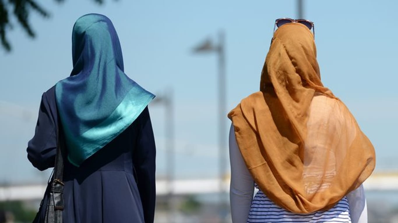 Zwei Frauen mit Kopftüchern gehen in Frankfurt spazieren.