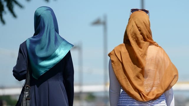 Zwei Frauen mit Kopftüchern gehen in Frankfurt spazieren.