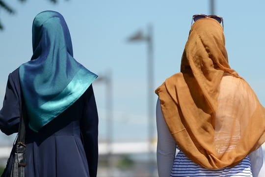 Zwei Frauen mit Kopftüchern gehen in Frankfurt spazieren.