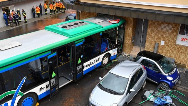 Der beschädigte Schulbus an der Fassade eines Hauses.