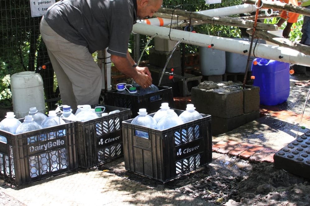 Mann befüllt Wasserkanister: Wegen anhaltender Dürre in Kapstadt ist die Wassserversorgung drastisch reduziert worden und auf 50 Liter Trinkwasser pro Tag pro Person beschränkt.