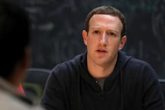 Facebook-Gründer Mark Zuckerberg: Nutzer vor Facebook-Logo: Nutzer des Netzwerks sollen über die Qualität von zitierten Medien entscheiden.