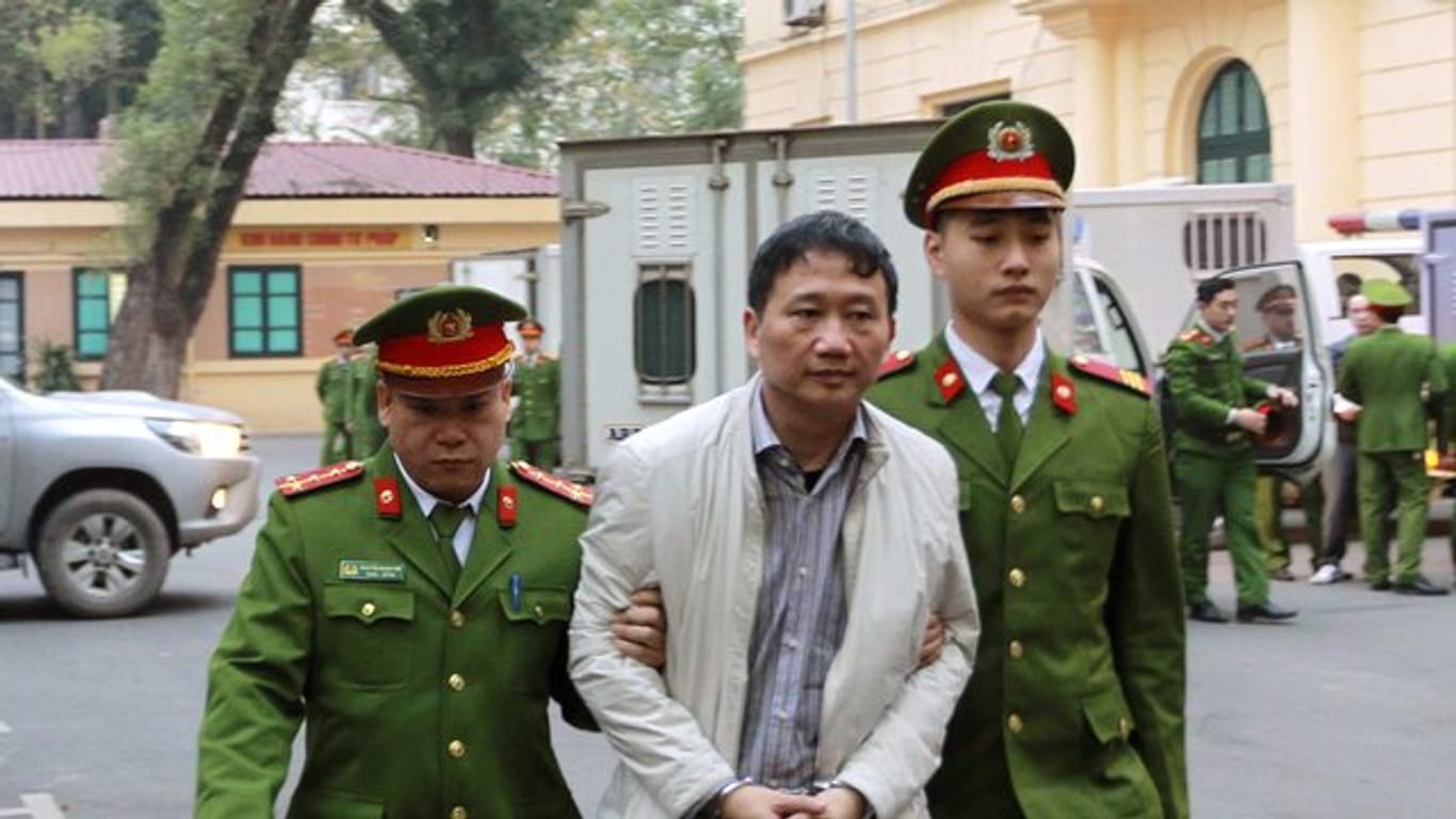 Polizisten bringen den angeklagte Geschäftsmann Trinh Xuan Thanh (M) in ein gericht in Hanoi.