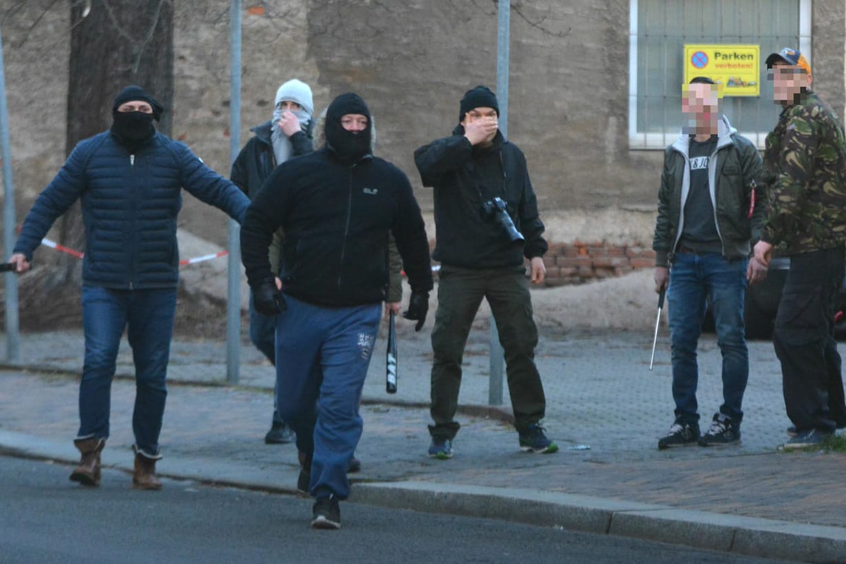 Bewaffnete Neonazis stürmen vom Grundstück eines Sonnenstudios auf Journalisten und linke Demonstranten zu.