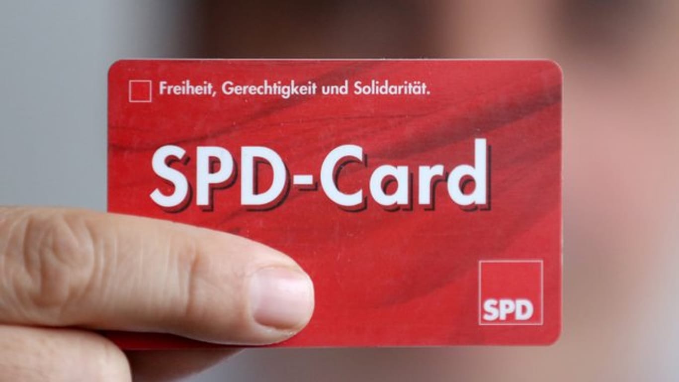 Ein SPD Mitglied zeigt sein Parteibuch im Checkkartenformat.