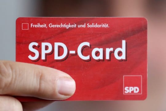 Ein SPD Mitglied zeigt sein Parteibuch im Checkkartenformat.