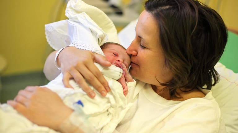 Mutter mit Kind im Arm: Immer häufiger kommen Babys per Kaiserschnitt zur Welt – obwohl der Eingriff oft nicht nötig ist.