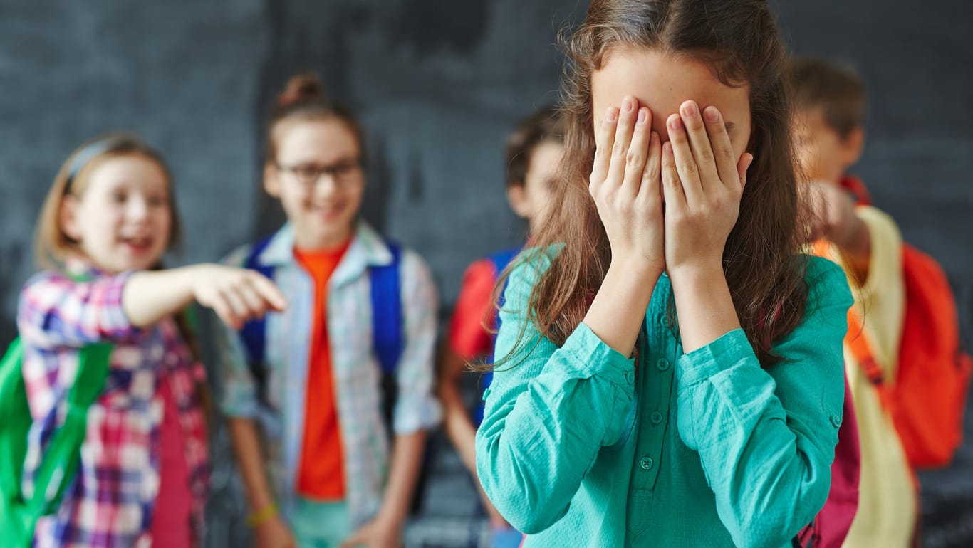 Kinder machen sich über Mitschülerin lustig: Mobbing ist eine Form der psychischen Gewalt.